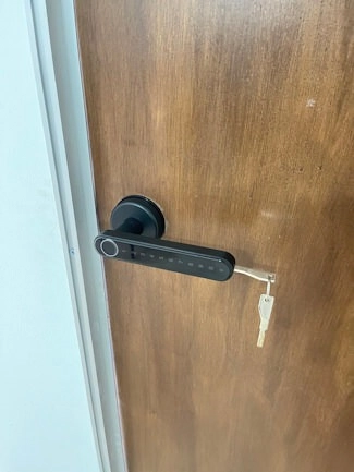 A smart door lock fitted to a wooden room door.