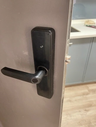 A smart door lock handle installed on a unit door.