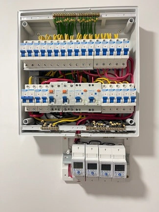 A completed distribution board with a row of smart meters fitted beneath it.